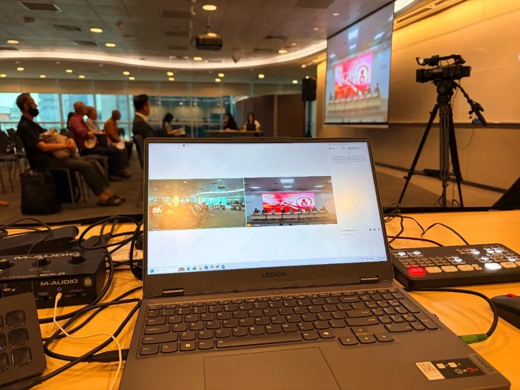 Production desk at a hybrid AGM: VooV Meeting showing the Singapore room and the China room, with shareholders seated and the China feed on the projector.